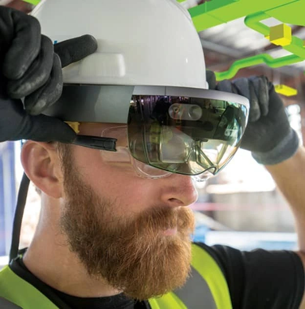 A PennDOT worker holds a pair of black and silver mixed reality smartglasses up to his eyes.